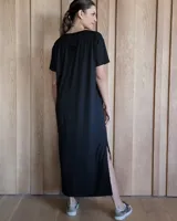 Vestido negro de corte recto, largo midi, con escote en V y mangas cortas.