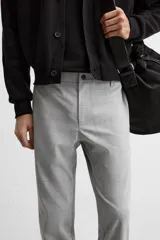 Pantalón negro de corte slim fit, confeccionado en tejido elástico. Cuenta con cintura elástica, bolsillos frontales y traseros de vivo. Cierre frontal con cremallera y botón.