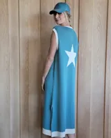 Vestido largo celeste de punto con cuello redondo y sisas ribeteadas en blanco. Estampado de estrella blanca en la espalda y abertura lateral en el ruedo.