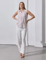 Camisa sin mangas de lino a rayas verticales azules y blancas, con cuello con solapa, escote en V, abertura central con botones y bolsillo en el pecho.