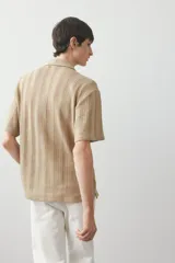Camisa de manga corta color beige en punto jacquard. Modelo con cuello inglés, tapeta clásica y bajo recto.