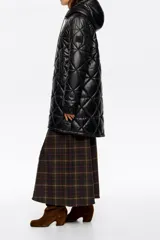 Abrigo largo de corte recto en tejido técnico negro con diseño acolchado de rombos. Presenta capucha integrada con cordones de ajuste, cierre frontal de cremallera, bolsillos laterales de vivo y mangas largas con puños elásticos. El bajo cuenta con elástico y stoppers interiores para un ajuste personalizado.