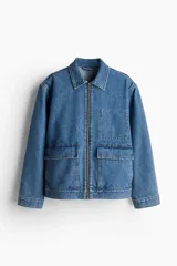 Campera de denim azul de algodón rígido con cuello, cierre delantero y canesú en la espalda. Modelo con puños abotonados, bolsillos delanteros con solapa y bolsillo interior de parche en el pecho. Trabillas ajustables con botones en la parte posterior del bajo.