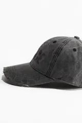 Gorra de lona de algodón color gris oscuro con estampado frontal de la palabra "VENCE" en letras grandes. Tiene detalles desgastados en la visera y ojales bordados. Cuenta con cinta antitranspirante de algodón y hebilla ajustable de metal en la parte trasera.