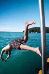 Short de baño negro con estampado geométrico en tonos naranja y blanco, con ribete rojo en el ruedo y logo de la marca en la pierna izquierda.