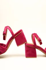 Sandalia de terciopelo verde con taco cuadrado de 7 cm, punta cuadrada y tiras anchas anudadas en el empeine. Cuenta con una tira fina ajustable al tobillo con hebilla dorada.