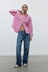 Camisa de popelín a rayas verticales rosas y blancas, de corte holgado, con cuello solapa, escote pico y mangas largas con puños abotonados.