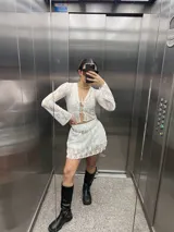 Conjunto de encaje blanco, compuesto por una chaqueta con lazos y una minifalda.