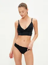 Conjunto de ropa interior negro, compuesto por un bralette de encaje con breteles finos y una bombacha tipo colaless de encaje.