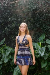 Vestido corto de lentejuelas color verde oliva, con escote en V, breteles finos cruzados en la espalda, cut-outs laterales y volado en el ruedo.