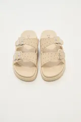 Sandalias bajas color beige con doble tira con hebilla y apliques de tachas.