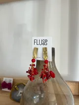 Aros colgantes hechos a mano con base dorada y mix de cristales, corales y piedras en tonos rojos.
