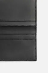 Tarjetero negro de cuero con costura central y cuatro ranuras para tarjetas.
