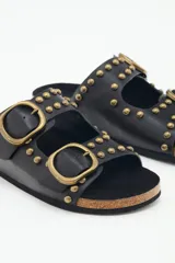Sandalias negras de cuero con tachas metálicas y hebillas doradas. La plantilla es de corcho y la suela de goma eva.