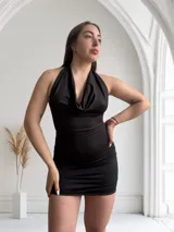 Minivestido negro de satén con escote halter y espalda descubierta.