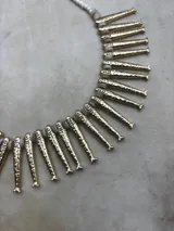 Collar dorado con dijes en forma de peces y cuentas blancas.