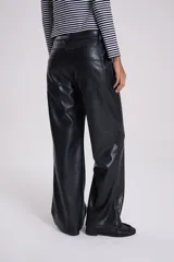 Pantalón recto de cuero sintético negro, estilo jeanero con tiro bajo, bolsillos delanteros y traseros, pretina con botón y pasacintos.