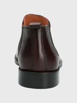 Bota Chelsea de cuero color vino (bordó oscuro) con puntera cuadrada y elástico lateral negro. Posee suela negra con costura de vira visible en color marrón claro.