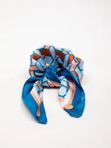 Pañuelo cuadrado con estampa geométrica en tonos azules y terracota.