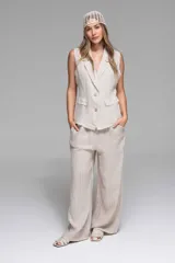 Pantalón de lino color beige con rayas verticales, pierna ancha y cintura elastizada en la parte trasera.