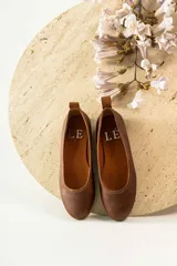 Zapato tipo ballerina color beige con correa al tobillo desmontable.