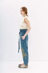 Pantalón de jean tiro alto con corte paper bag, lazo a tono en la cintura y bordado con lentejuelas y piedras en el lateral.