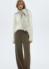 Pantalón de jogging color verde oliva, de corte ancho y tiro medio, con cintura elástica ajustable con cordón. Presenta costuras verticales decorativas en el frente y bolsillos laterales.