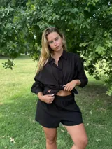 Conjunto negro de camisa de manga larga con botones y shorts.