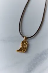 Dije dorado con forma de bota cowboy con detalles calados.
