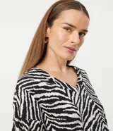 Blusa de viscosa con estampado animal print en blanco y negro, escote en V, mangas largas abullonadas con puños ajustados y dobladillo mullet.