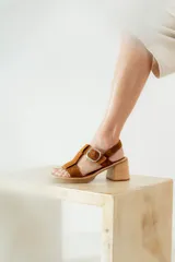 Sandalias negras de charol con tiras entrecruzadas, hebilla dorada y tacón de madera.