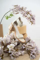 Sandalias de cuero color crudo, con tira ancha sobre los dedos, pulsera con hebilla al tobillo y taco cuadrado de madera.