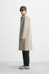 Gabardina color beige de corte relaxed fit, confeccionada en tejido italiano repelente al agua. Tiene cuello solapa, manga larga con puños abotonados, bolsillos de vivo en la cadera, bolsillo interior y abertura en la espalda.