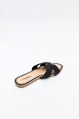 Sandalia baja negra con capellada trenzada tipo cordón, suela plana con bordado a tono.