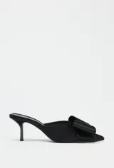 Zapato tipo mule de tacón fino, color negro, con punta fina y maxi lazo decorativo en la parte delantera.