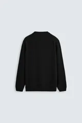 Jersey negro de corte boxy fit, tejido en hilatura con mezcla de algodón y 13% de cashmere. Tiene cuello redondo, manga larga y acabados en rib.