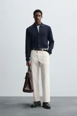 Pantalón chino de vestir negro, corte slim fit, con bolsillos laterales y traseros. Cierre frontal con cremallera y botón.