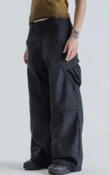 Pantalón negro con corte ancho, bolsillos laterales con solapa y detalle de cierre a la altura de la rodilla para convertirlo en short.