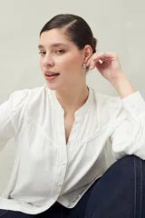 Camisa blanca de manga larga con cuello redondo y escote en V. Confeccionada en viscosa de caída suave, con detalles de pasamanería en el frente y las mangas.