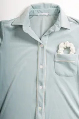 Pijama celeste de terciopelo, compuesto por una camisa de manga larga con botones y vivo blanco, bolsillo en el pecho y un pantalón recto con elástico en la cintura.