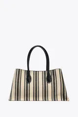 Bolso tipo shopper de mano confeccionado en canvas color crudo con rayas verticales negras. Tiene tiras interiores con cierre de mosquetón metálico, bolsillo interior con cierre de cremallera metálica y cierre imantado.