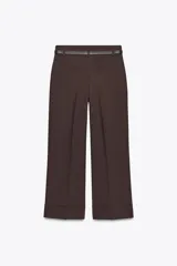 Pantalón marrón de tiro alto con cinturón negro, bolsillos delanteros y cierre frontal con cremallera y gancho metálico.