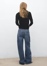 Jersey de punto fino color negro con cuello de pico y ribetes en contraste blanco en el cuello y puños. Diseño recto y manga larga.