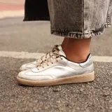 Zapatillas urbanas plateadas de cuero, con cordones finos color beige y suela de goma color caramelo.
