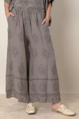 Pantalón palazzo de lino color crudo con estampado floral al tono, tiro alto y cintura elastizada.