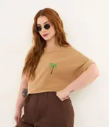 Remera de algodón texturizado color camel, con cuello redondo, manga corta con bajo plegado y un pequeño bordado de palmera en el pecho.