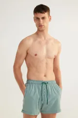 Short de baño de sirsaca a rayas verticales verdes y blancas, con aberturas laterales cortas, elástico y cordón ajustable en la cintura, bolsillos laterales, bolsillo trasero con cierre autoadherente y suspensor interior de malla.