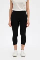Calza capri negra de algodón, tiro alto y corte ajustado.