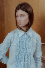 Camisa celeste de corte clásico con volados al frente y en los puños.