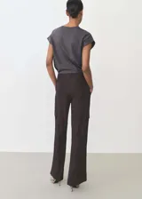 Camiseta gris con cuello en V, manga corta y detalle de tachuelas en los hombros.